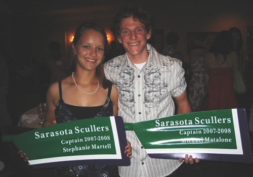 Two rowers pictured at an event with oar blades in hands which read "Sarasota Scullers Captain 2007-2008". One then says Stephanie Martell, the other Michael Matalone